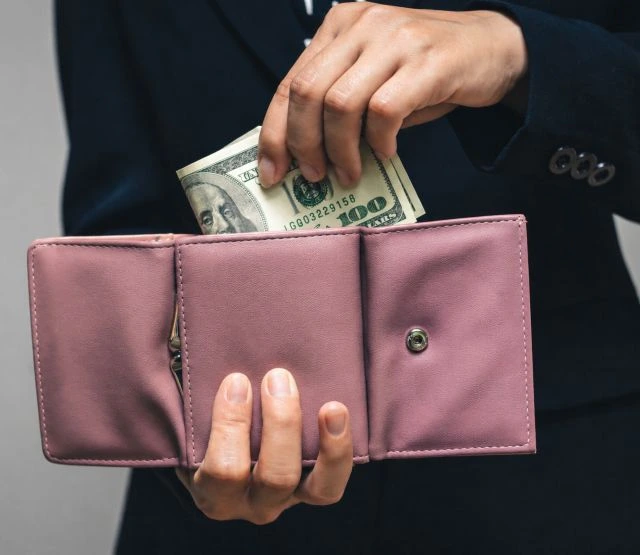 woman putting cash into her wallet